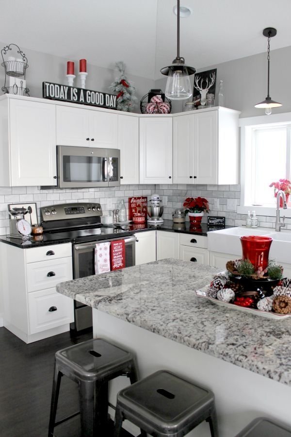 Christmas garland, pinecones, candles and a sign reading Today Is a Good Day arranged above white kitchen cabinets