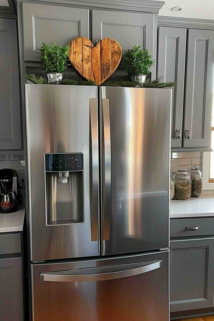 Stainless steel refrigerator styled simply with a wooden heart and two small potted plants