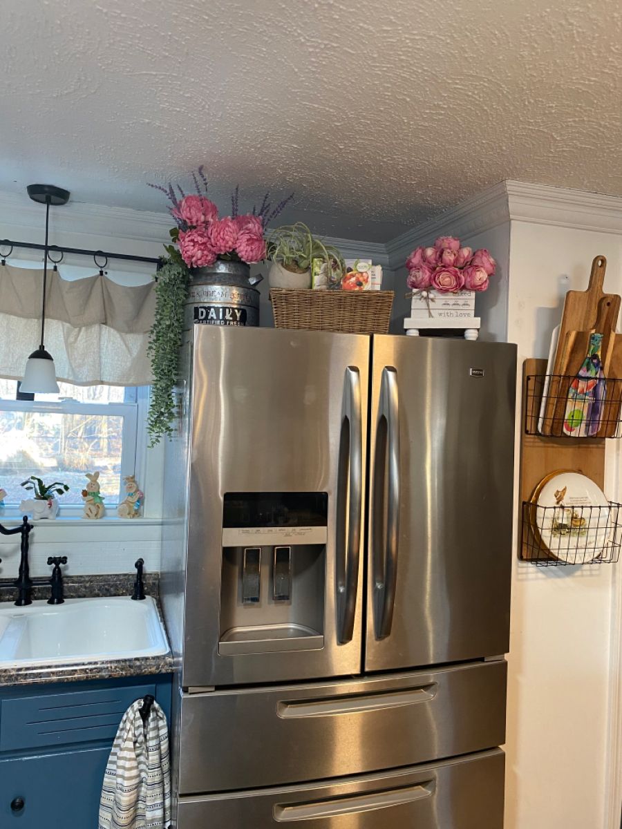 Pink floral arrangement in a vintage milk can styled above a stainless steel refrigerator