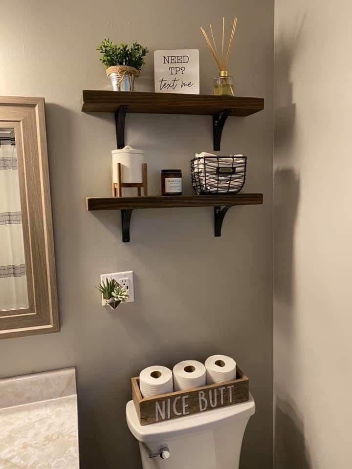 Open bathroom shelf styled with rolled towels and a small plant in a neutral palette