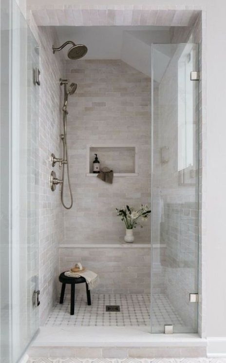 Walk-in glass shower with a wide rain showerhead and tiled bench built into the wall