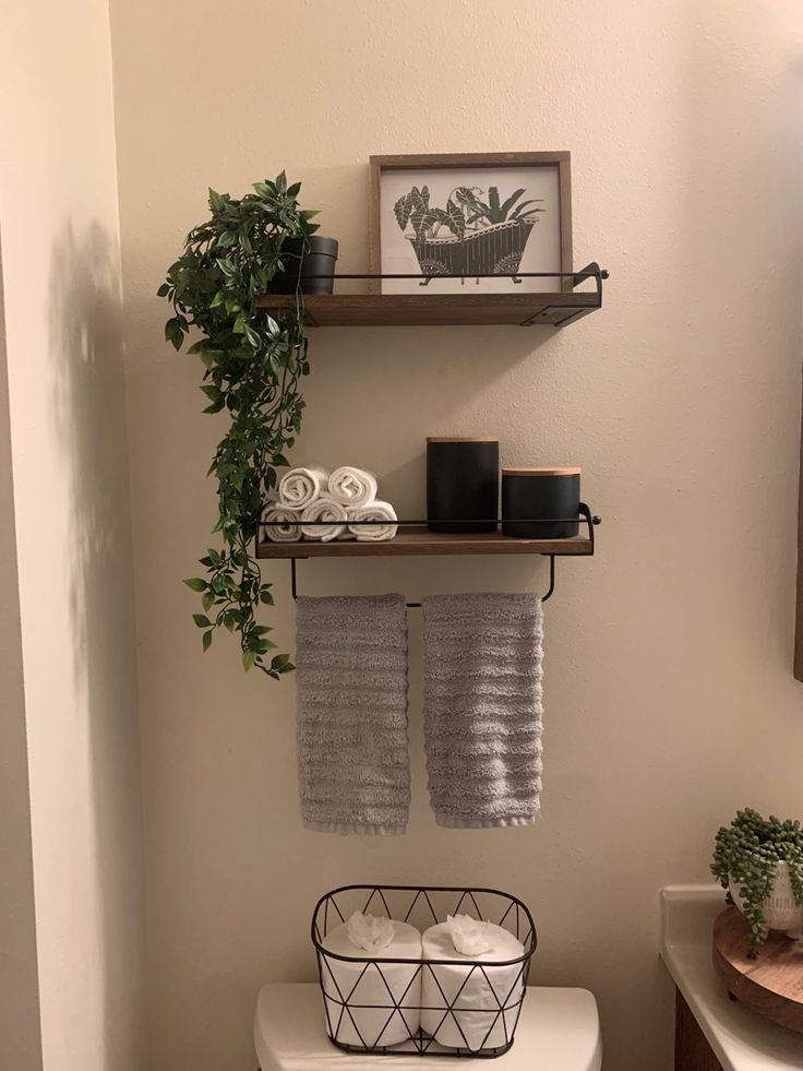 Framed botanical bathtub artwork leaned against the wall on a bathroom shelf with a diffuser and dried flowers