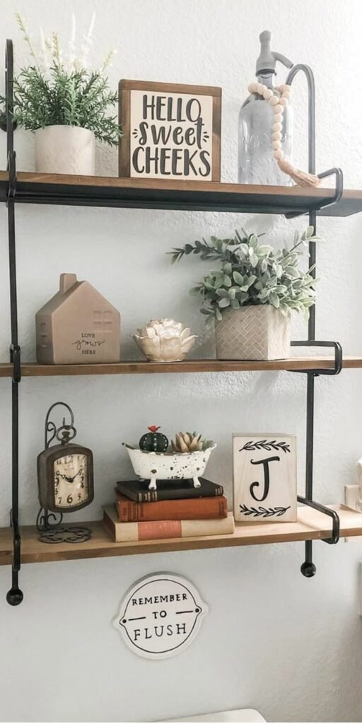 Bathroom shelves styled with a small ceramic house, a vintage clock, stacked books and a Hello Sweet Cheeks sign