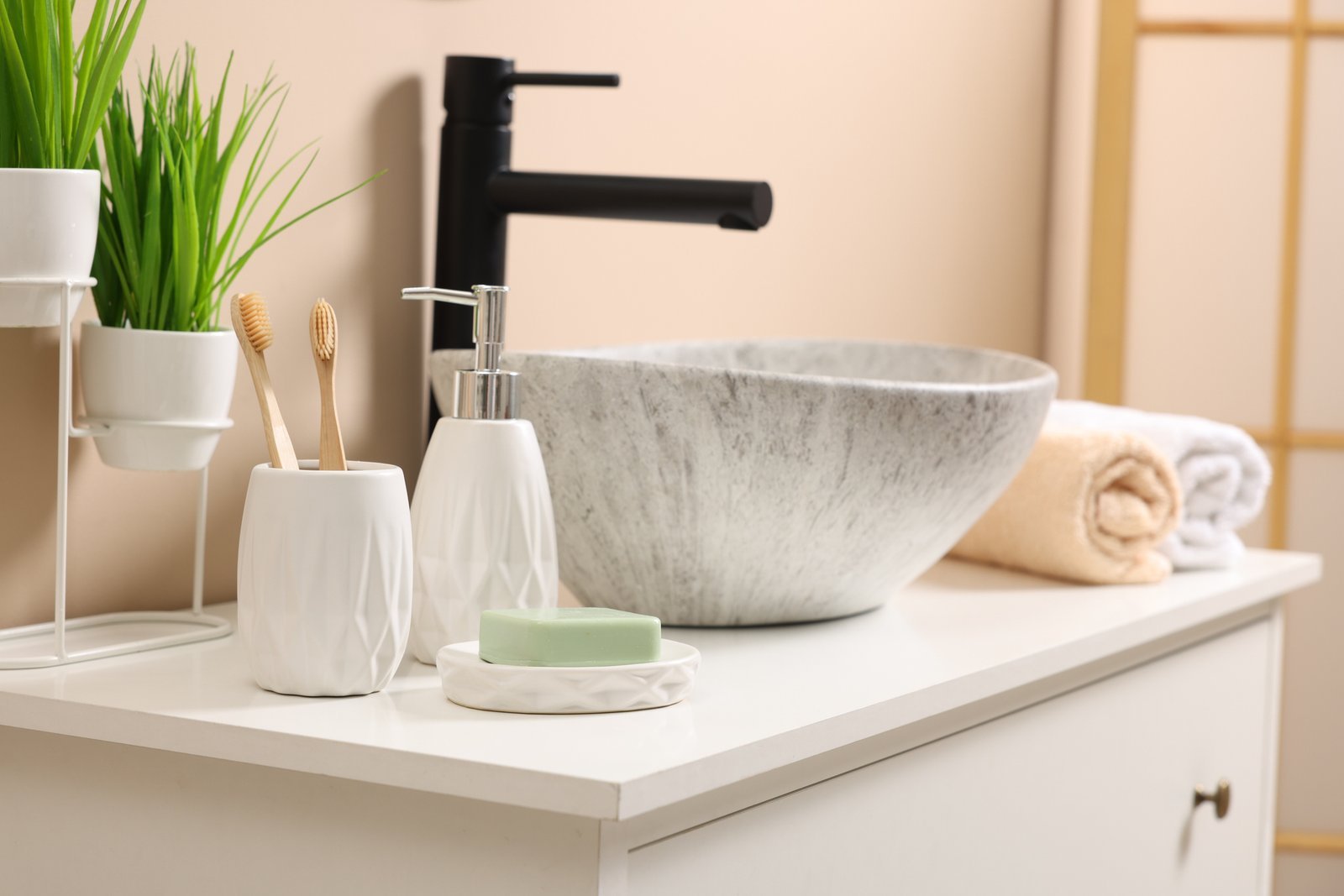 Styled bathroom sink with a soap dispenser, greenery and rolled towels