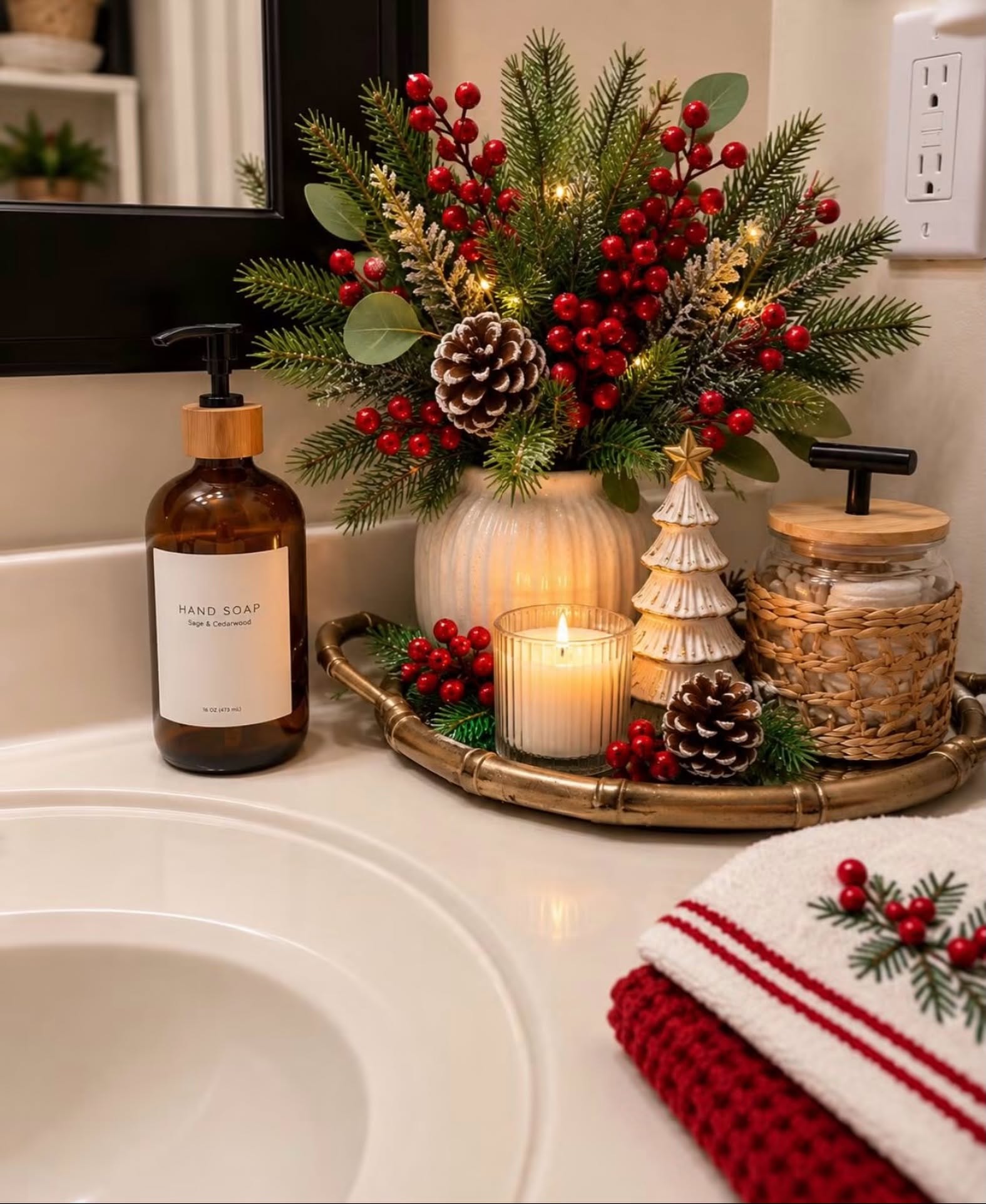 Gold tray with candlelit greenery and red berries on a bathroom counter