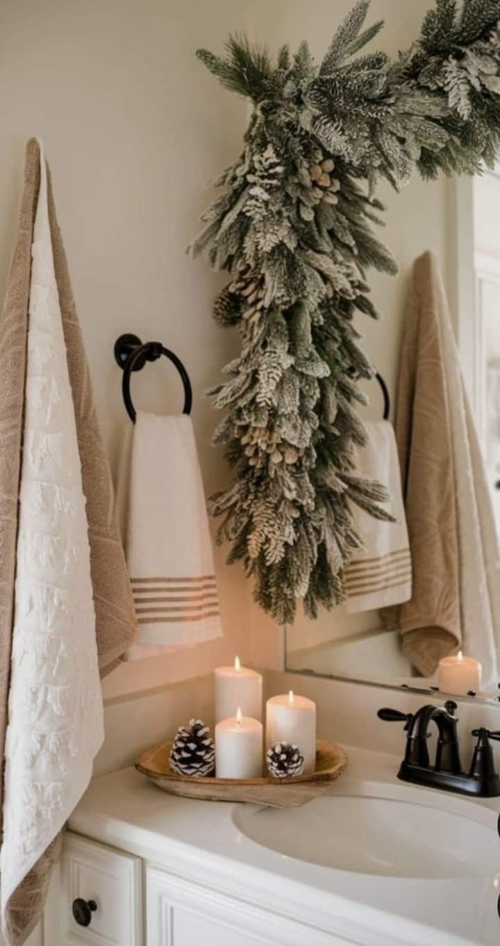 Snow-flocked Christmas garland draped over a bathroom mirror with lit candles