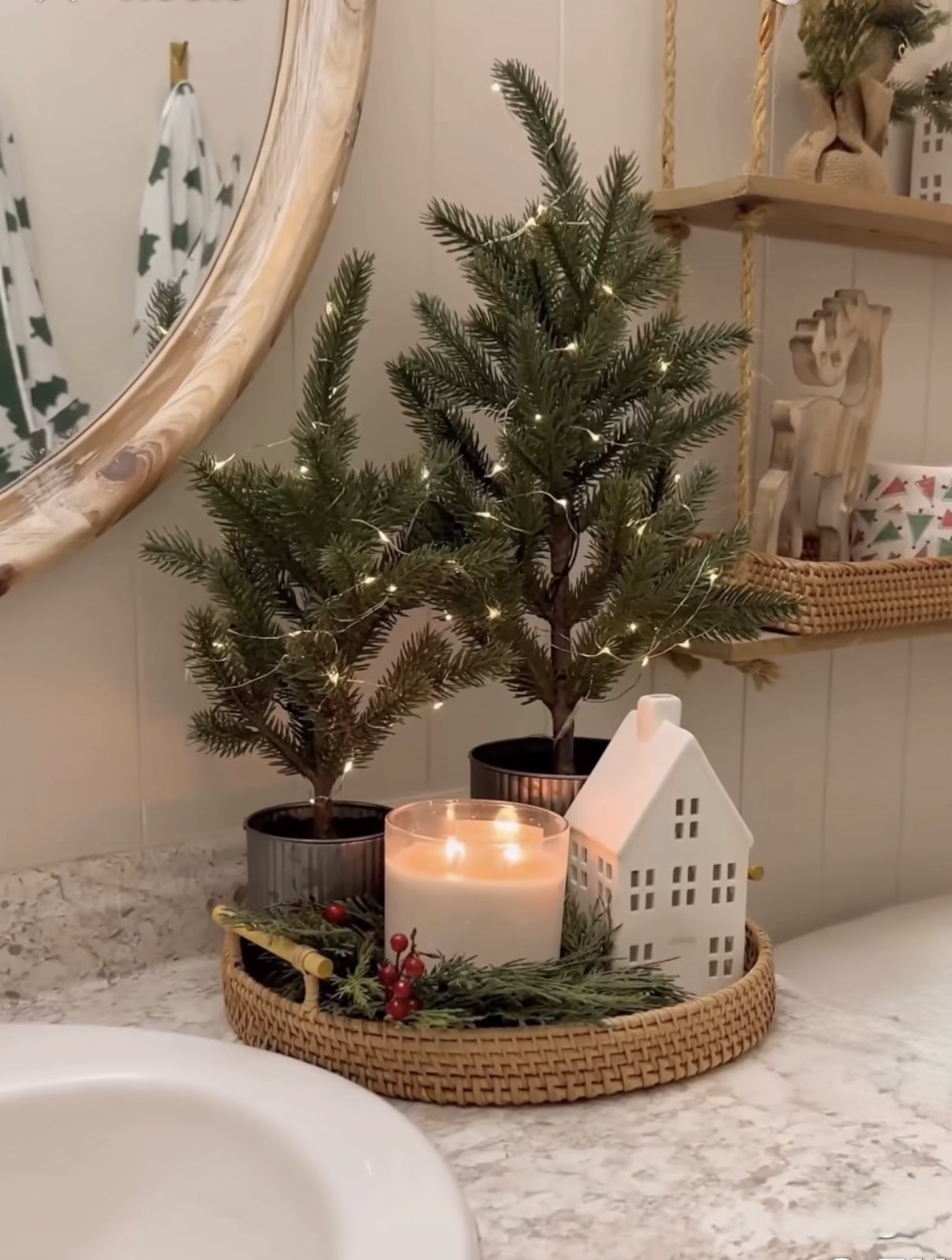 Candlelit wooden tray with mini Christmas trees and a small lit house