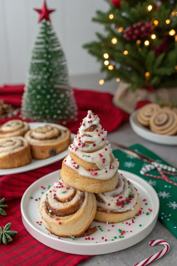 A stack of frosted cinnamon rolls arranged into a Christmas tree shape with sprinkles