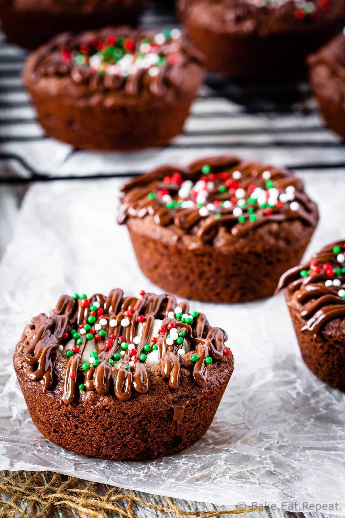 A hot chocolate brownie cup topped with chocolate drizzle and holiday sprinkles