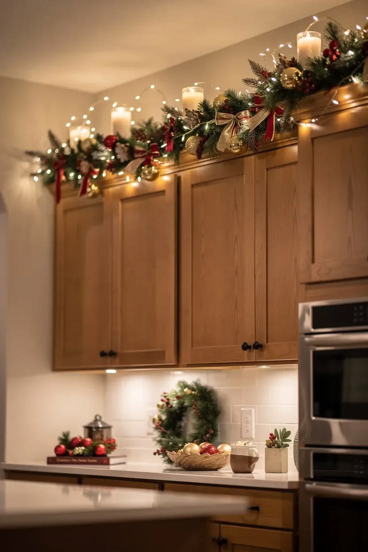 Garland with lights, candles, and gold ornaments draped above kitchen cabinets