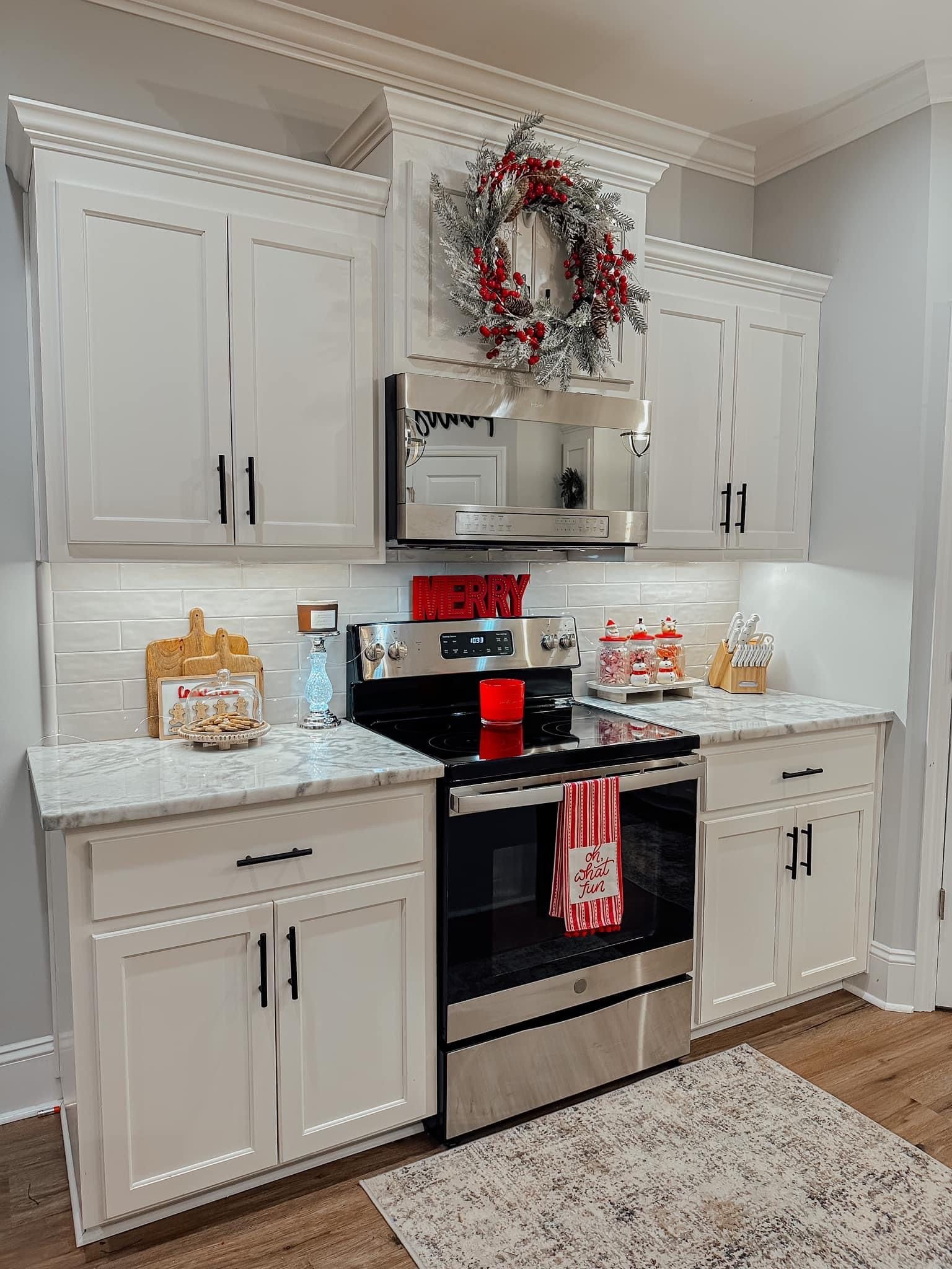 A greenery wreath over a stove with a bold Merry sign on the backsplash