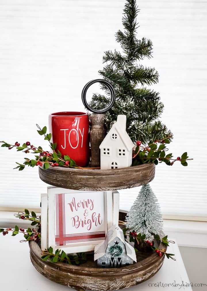 Two-tier tray with a red Joy mug, a small lit house, and fresh greenery