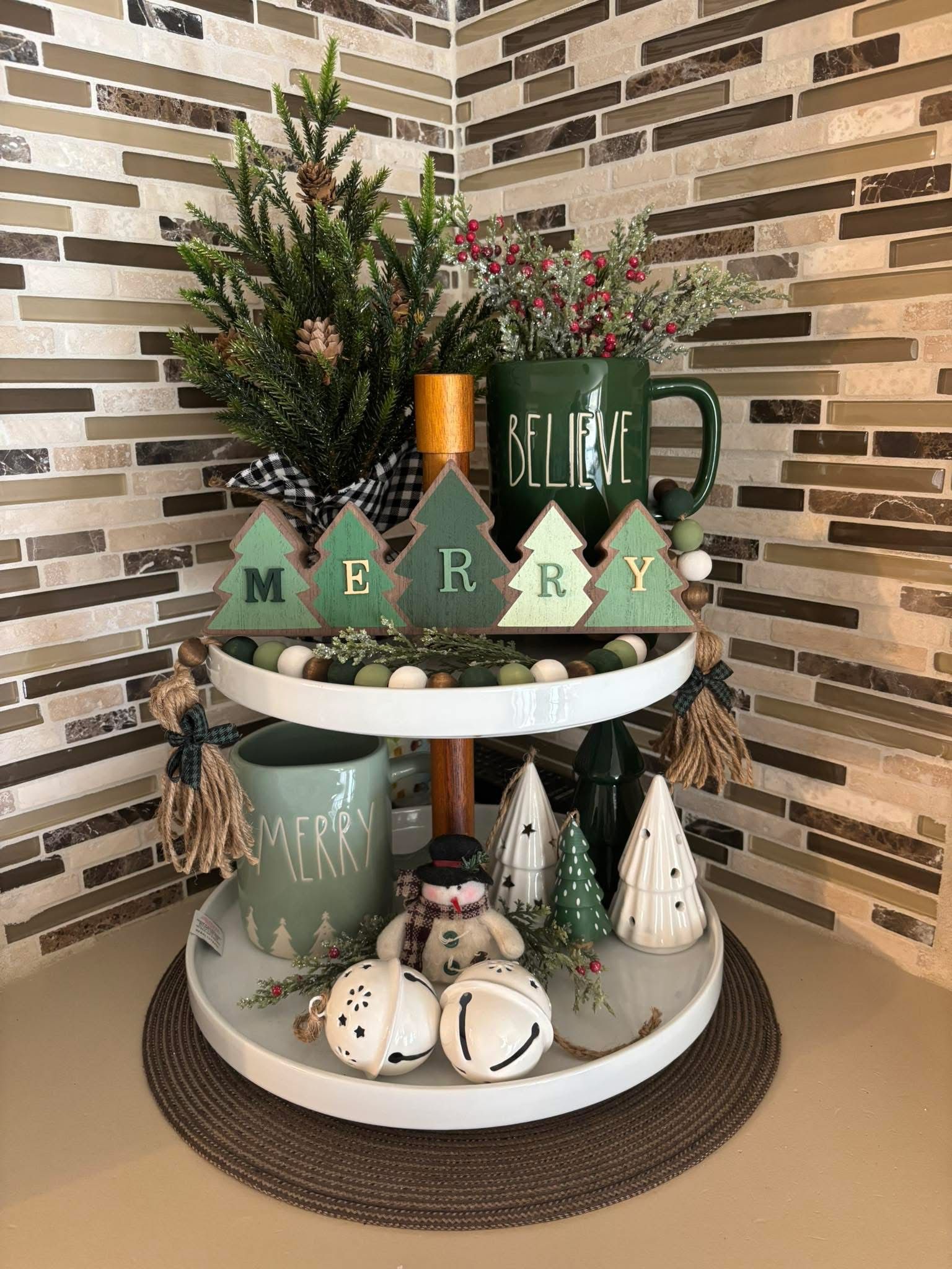 Tiered tray with wood tree letters spelling Merry and a green Believe mug