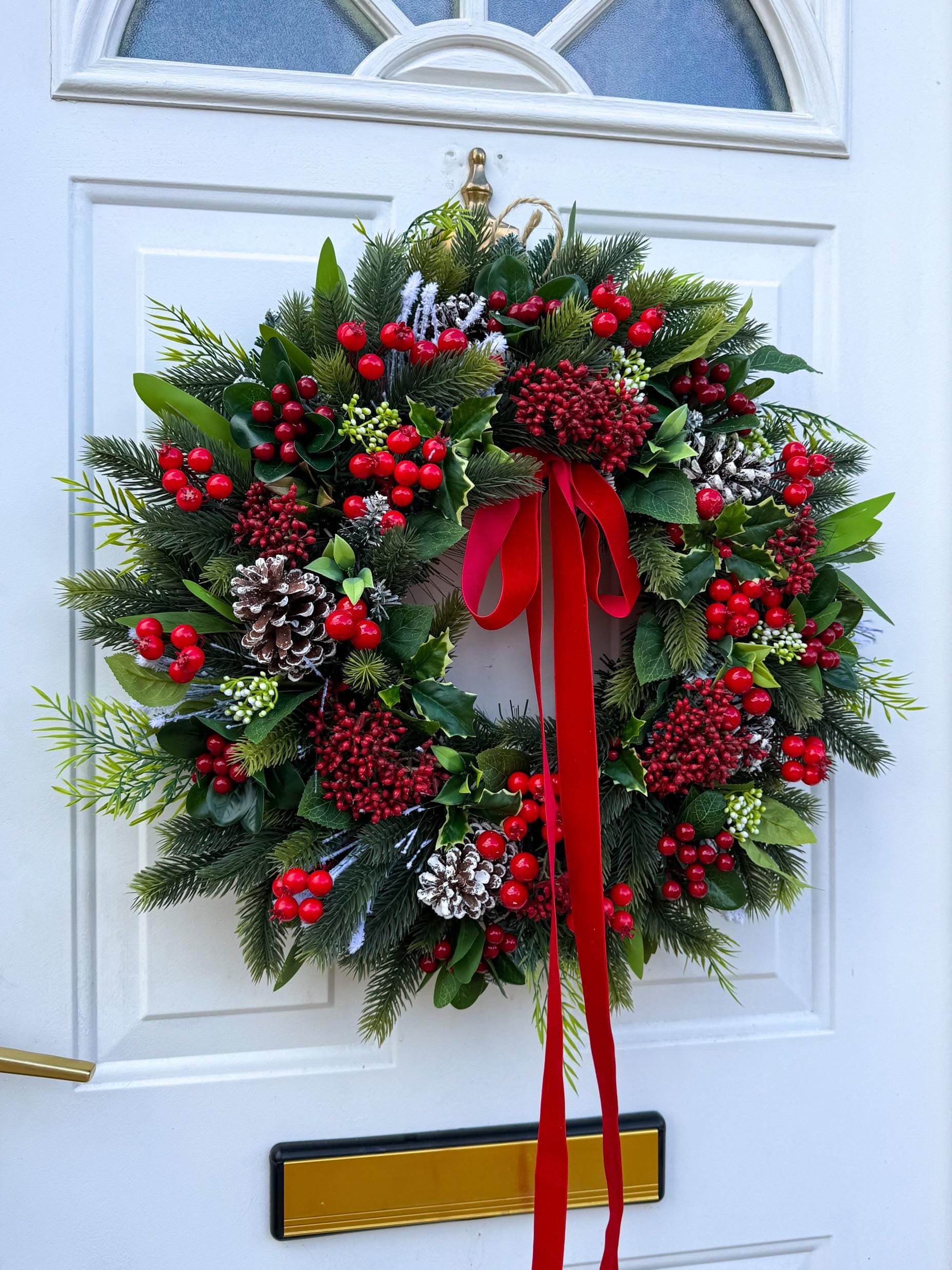 Full holly and berry Christmas wreath with a red velvet bow