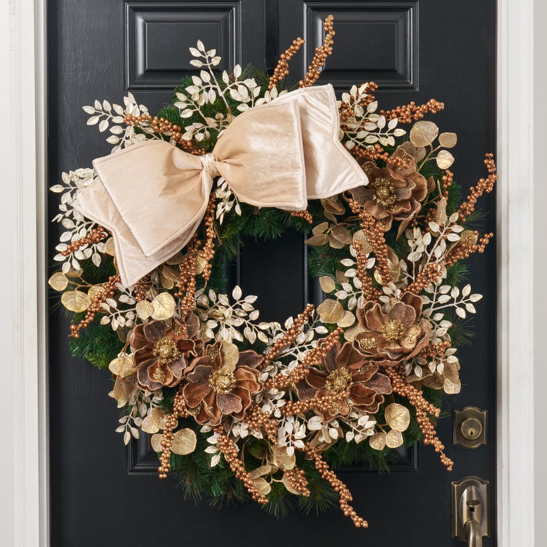 Brown velvet magnolia wreath with gold leaves and a cream bow on a black door