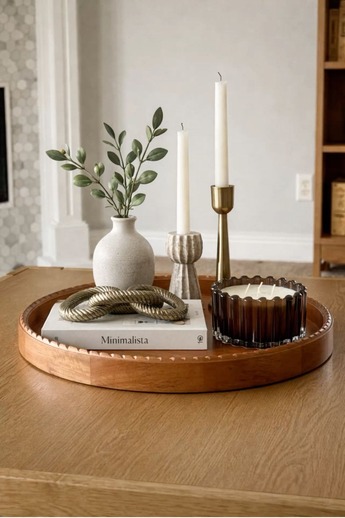 Round wood tray styled with a minimalist book, taper candles and a vase