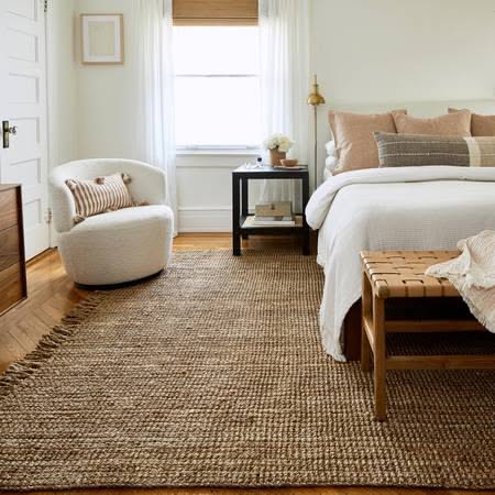Cozy cottagecore reading nook with a boucle chair and a natural jute rug