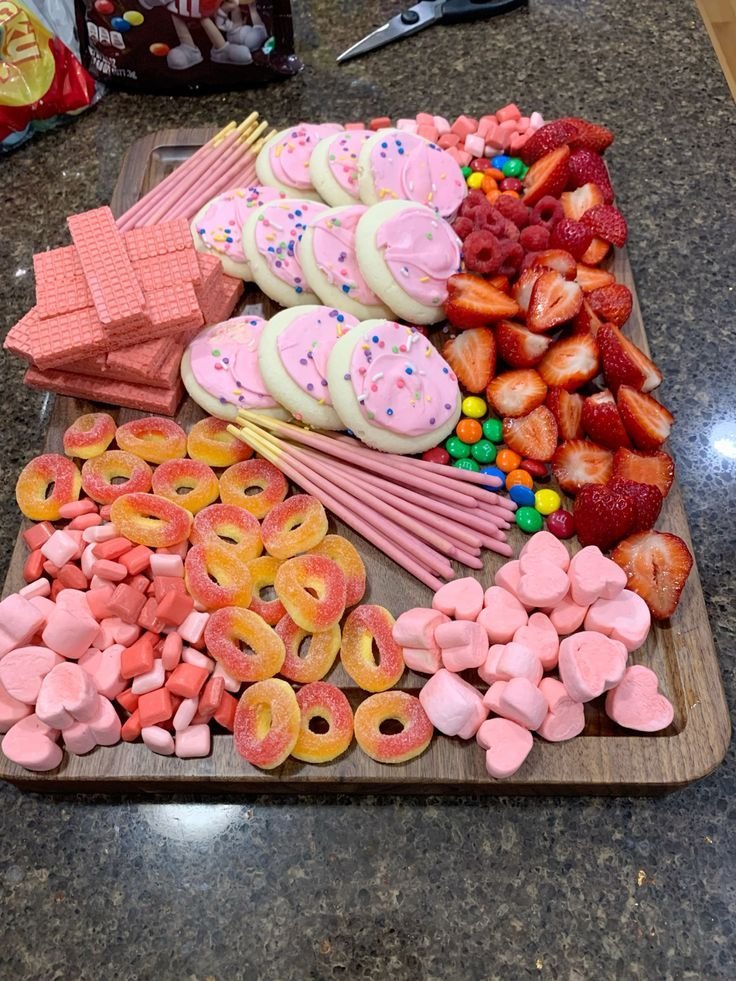 Pink dessert board with frosted pink sugar cookies, pink wafer bars, fresh strawberries, raspberries and pink heart marshmallows
