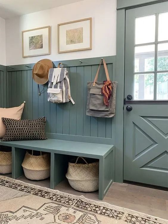 A teal green wainscot mudroom with a matching dutch door and a bench with two baskets
