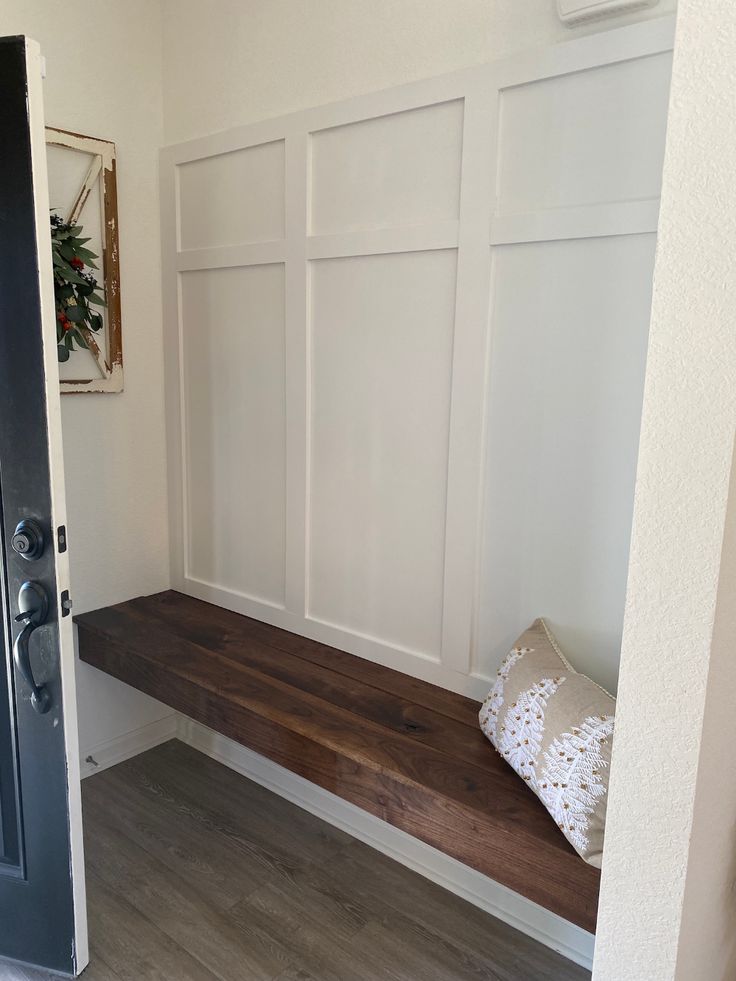 A floating walnut bench under a white board and batten wall