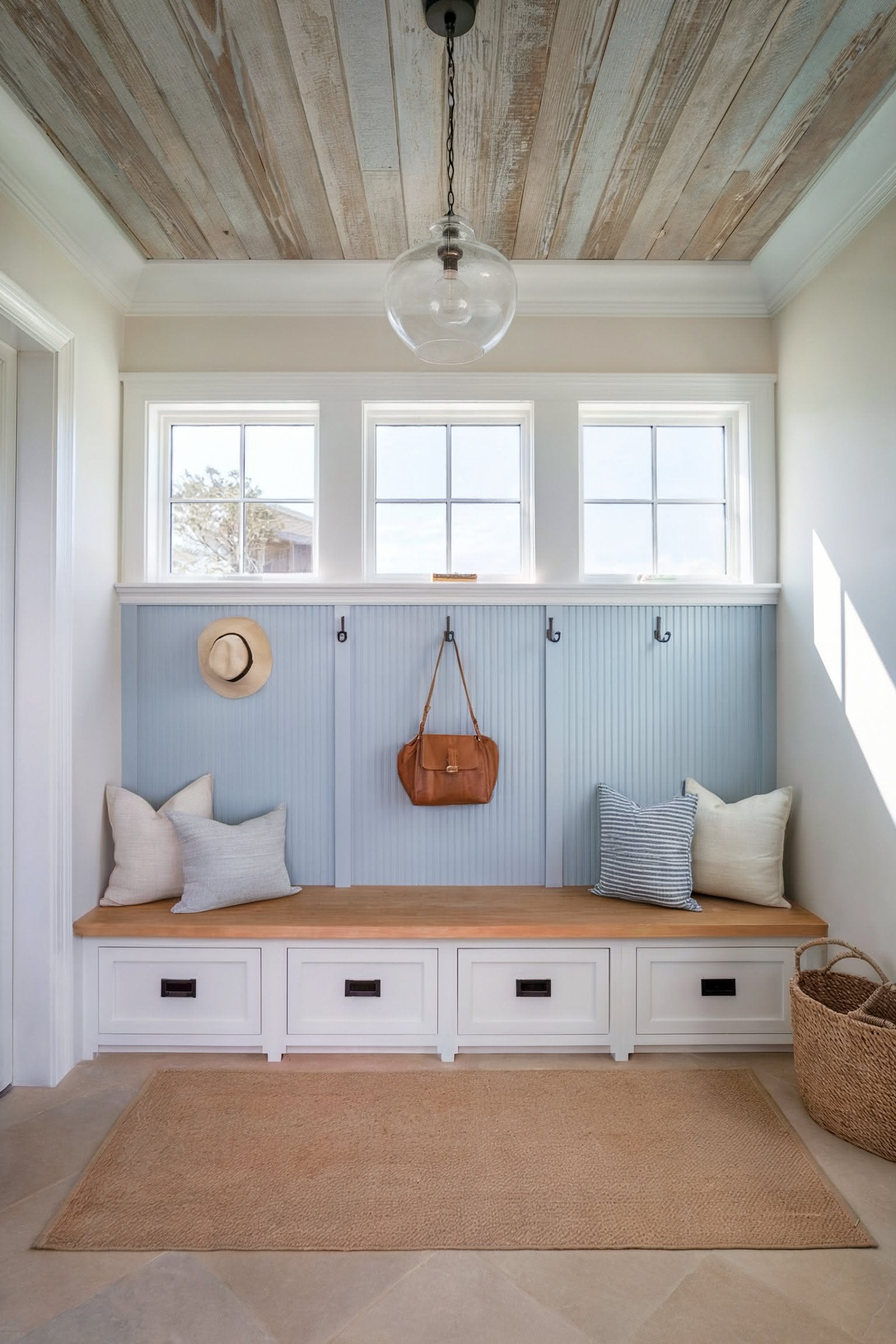A blue beadboard mudroom with a four-drawer bench and a whitewashed plank ceiling