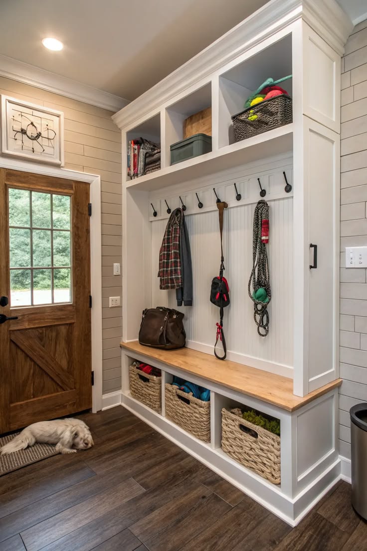 A white mudroom built-in with a leash on a hook, a basket bench and a dog resting nearby