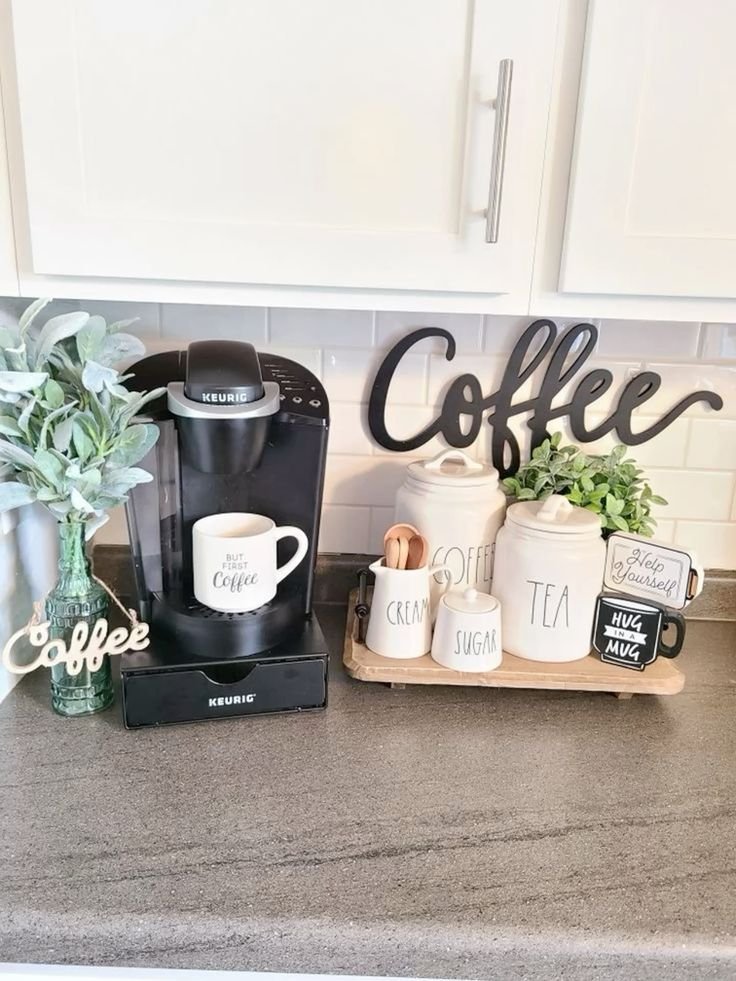 Compact coffee station on a dorm countertop with a Keurig machine, mugs, coffee and tea canisters and a wooden tray