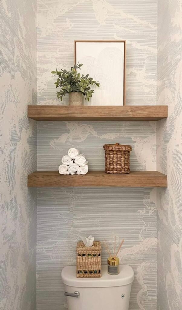 Floating wood shelves with minimal styled decor above a powder room toilet