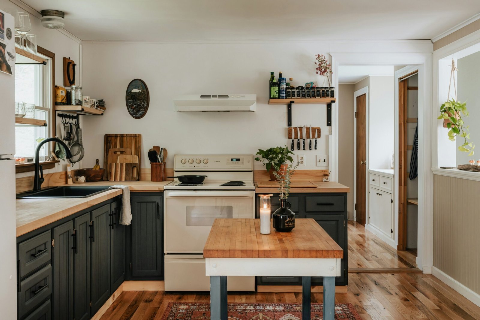 Farmhouse kitchen with dark green cabinets, butcher block countertops, open wood shelving and a small wood island