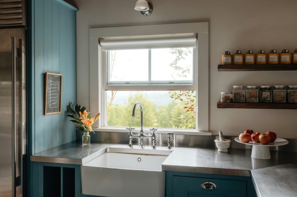 Blue vertical shiplap paneling wall beside a farmhouse sink with a bridge faucet and stainless steel countertop