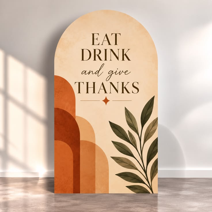 An arched sign reading Eat Drink and Give Thanks with a watercolor leaf design