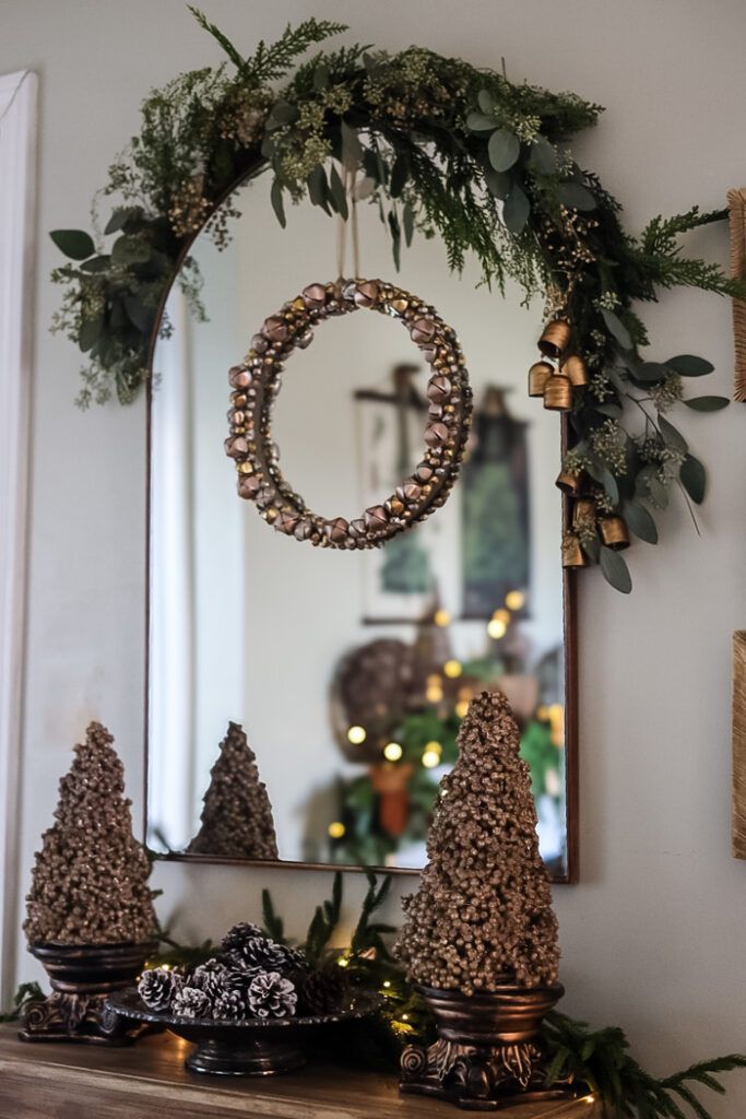 Gold jingle bell wreath hanging above bottle brush trees and pinecones