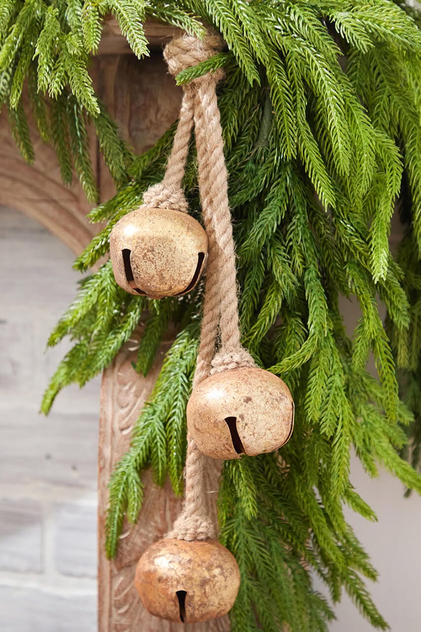 Close-up of rustic jingle bells tied with jute rope hanging from pine garland