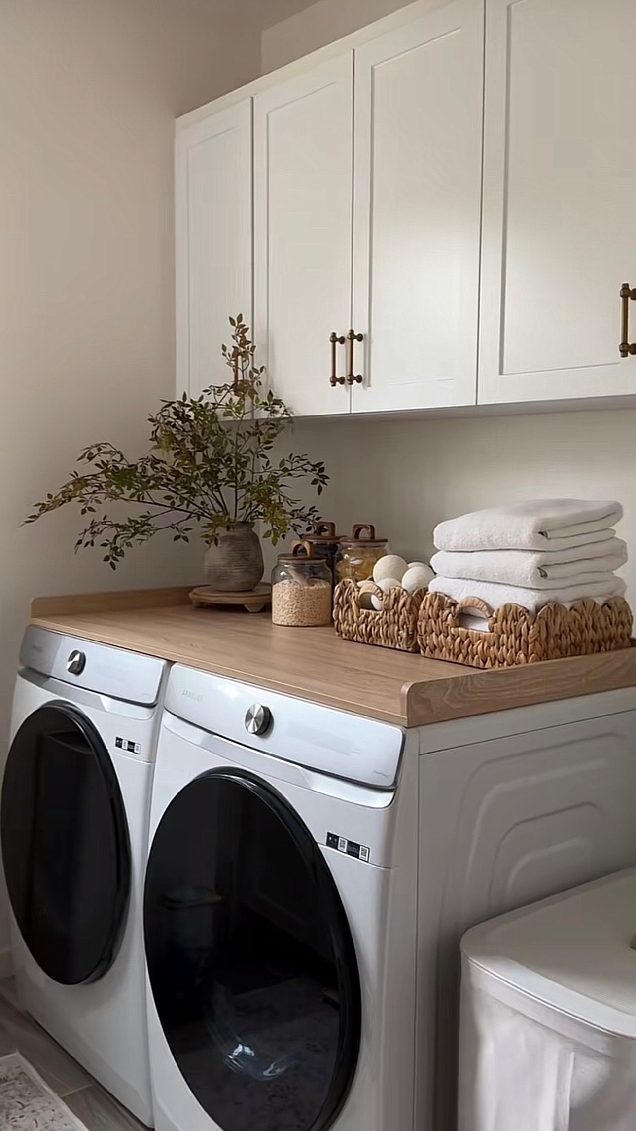 White laundry room cabinets with glass-front doors and matching jars beside a louvered closet door