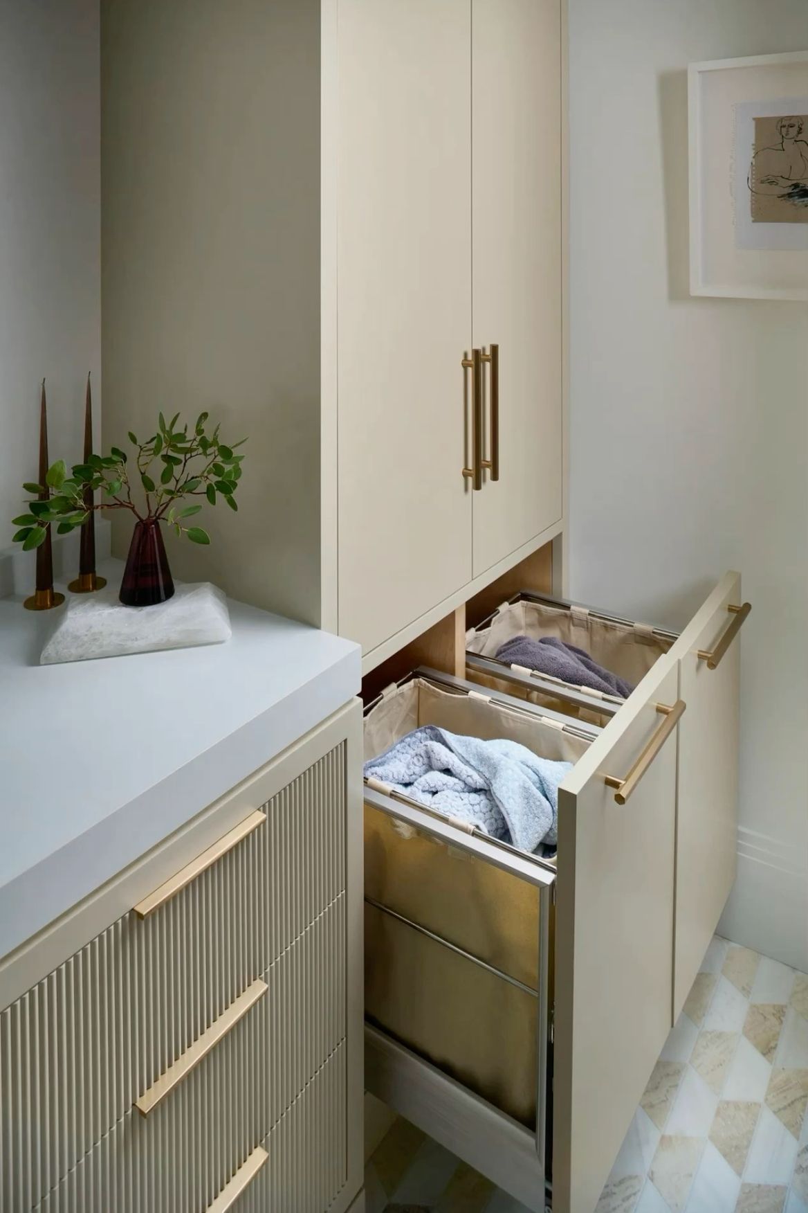 Built-in pull-out laundry hamper drawers with brass hardware in a luxury cabinet