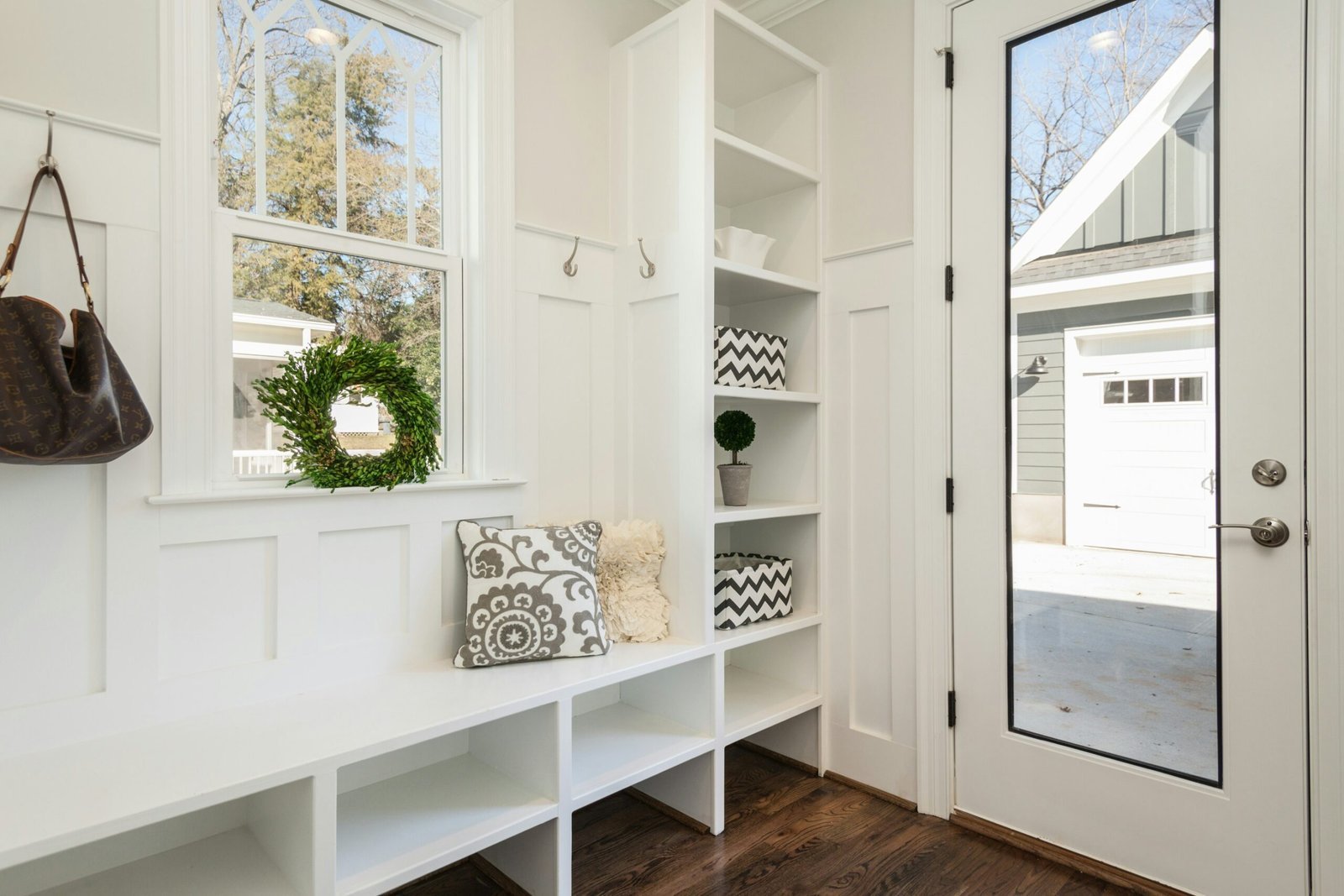Built-in mudroom bench with open storage cubbies, hooks and a window seat