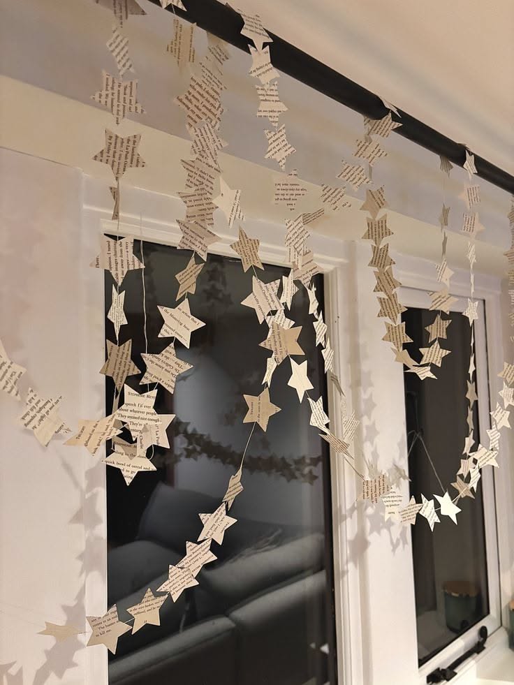 Garlands of paper stars cut from old book pages hanging in front of a window