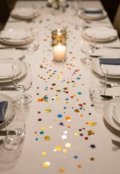 A white table runner scattered with colorful confetti between place settings