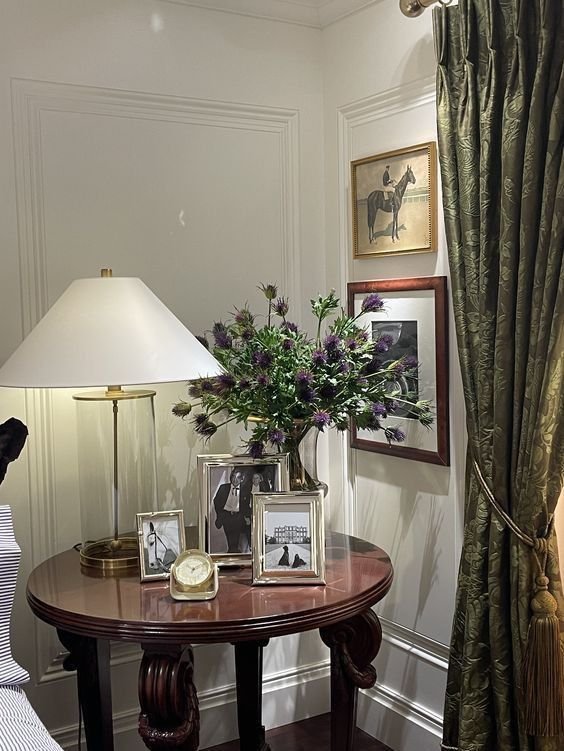 Small decorative clock styled among framed photos on a side table
