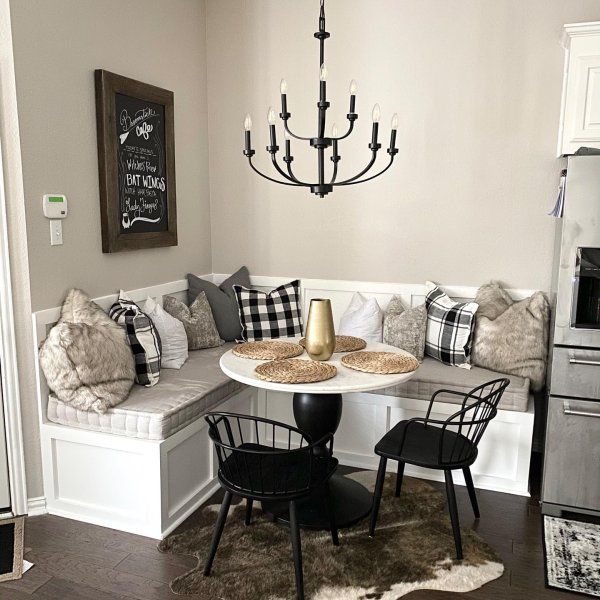 Built-in banquette bench with black chairs and a chandelier in a small dining corner