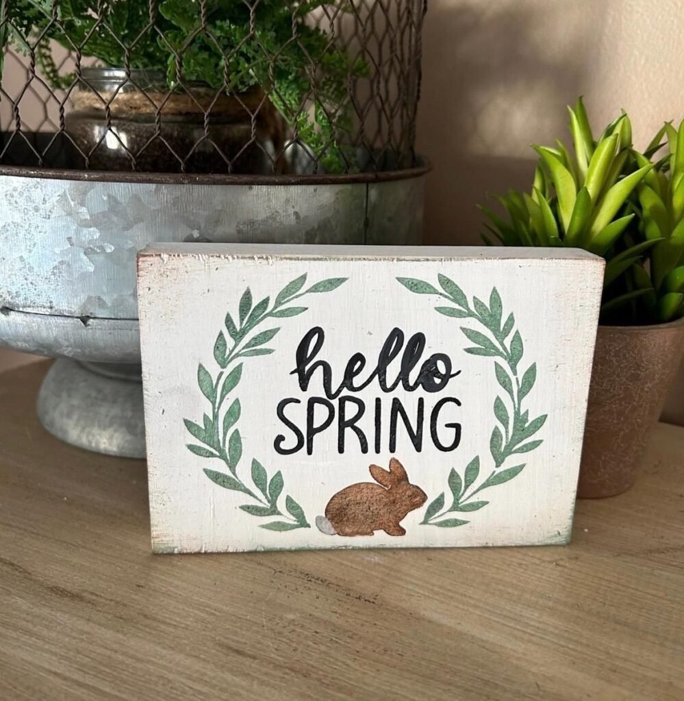 Hand-painted wooden sign with a short spring quote in a clean font