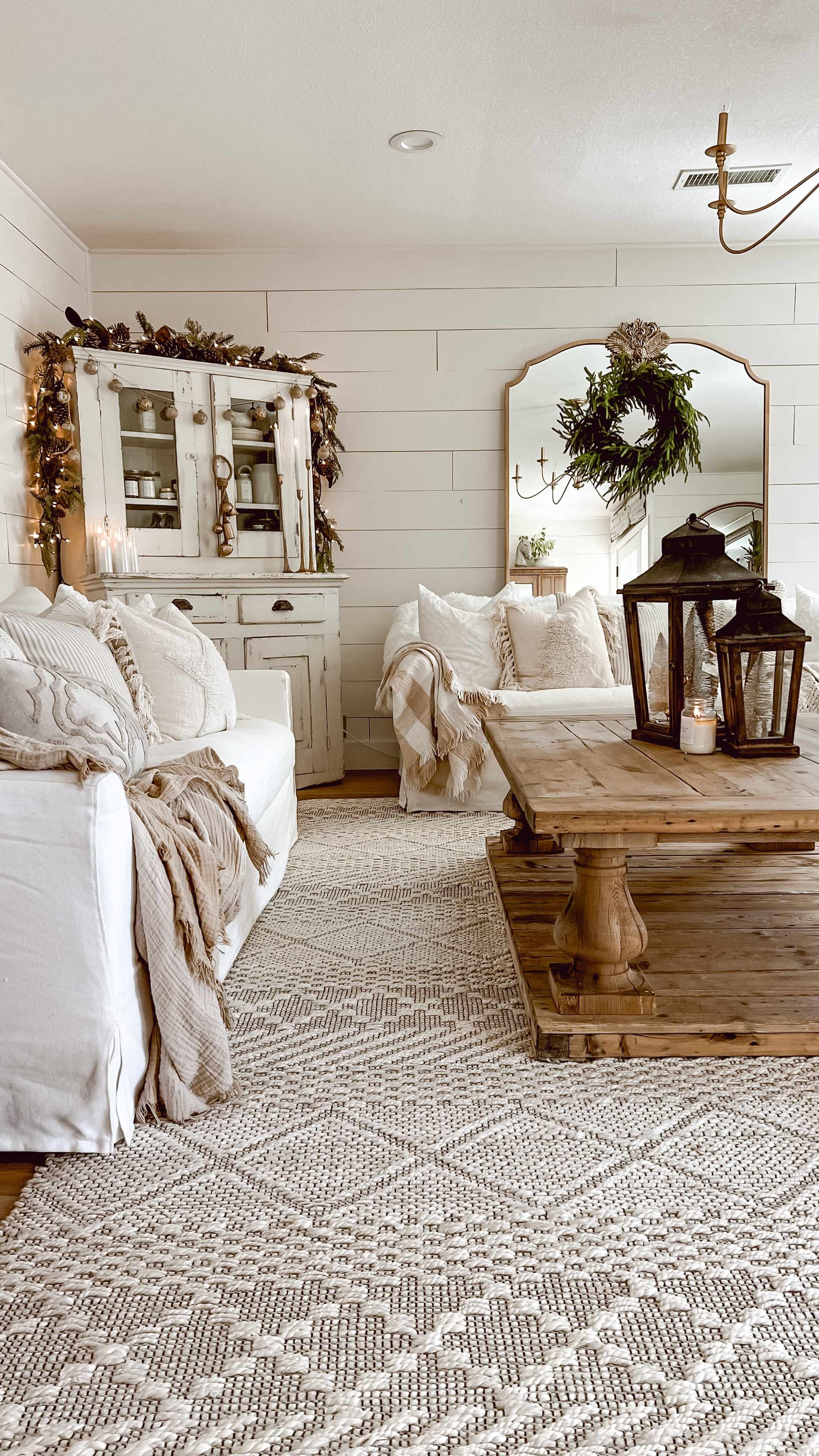Living room with a distressed antique white hutch decorated for Christmas beside a reclaimed wood coffee table