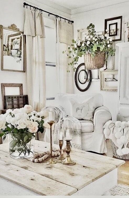 Shabby chic living room with a gallery of vintage mirrors and frames above a whitewashed wood coffee table