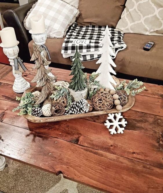 Dough bowl styled with three mini wood and greenery trees of different heights, twig balls, pinecones and a white snowflake ornament