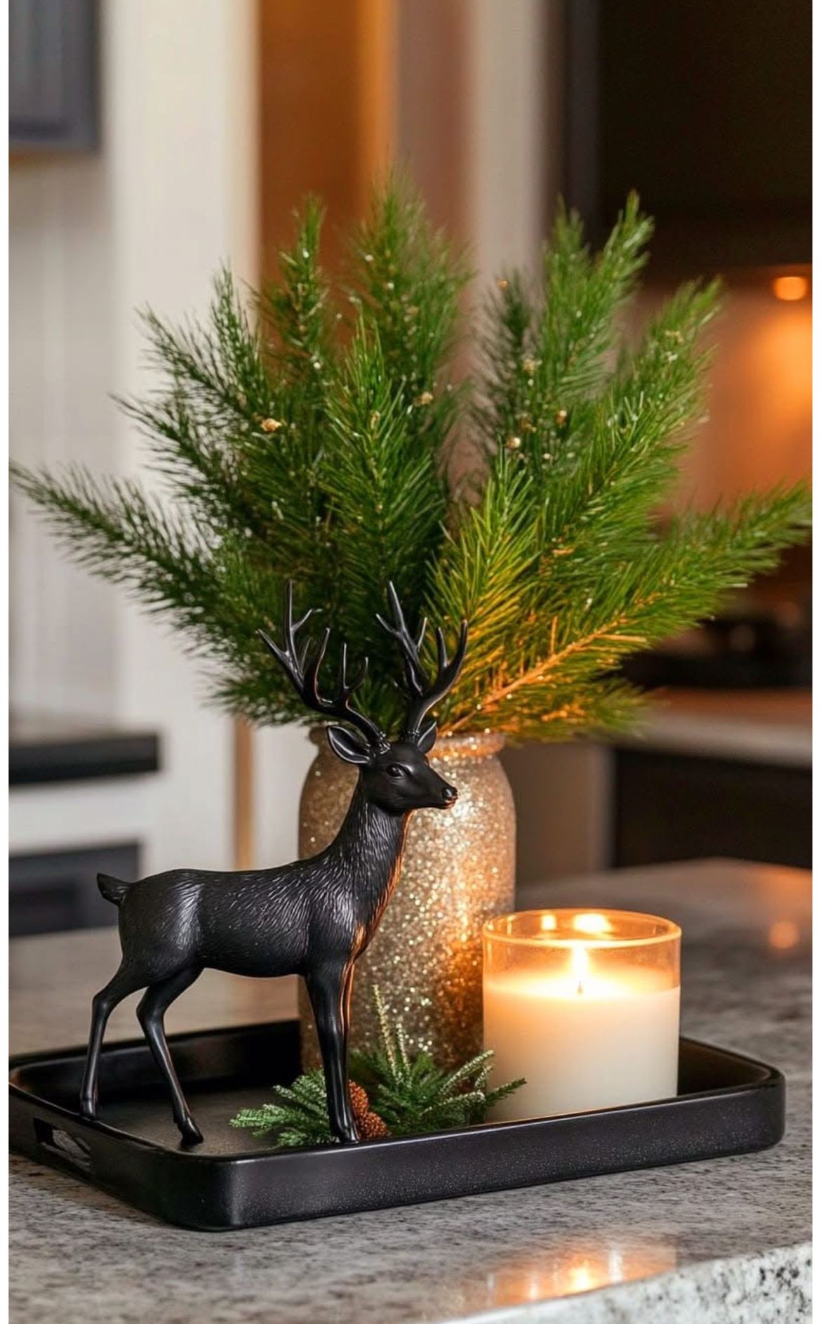 Black rectangular tray with a black deer figurine and a gold glitter vase of pine